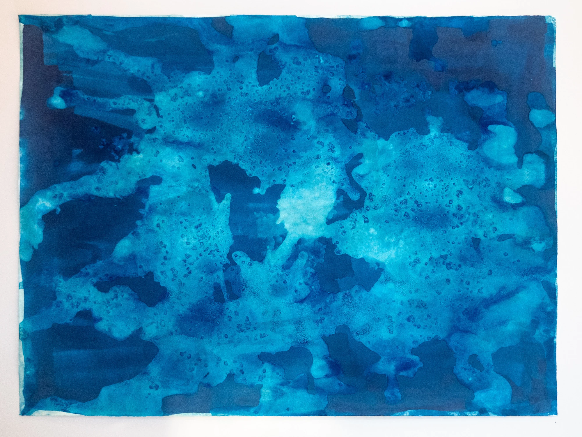Interlocking pale and dark blue floe shapes spreading edge to edge across the sheet, seen as if looking up at pack ice from underneath.

