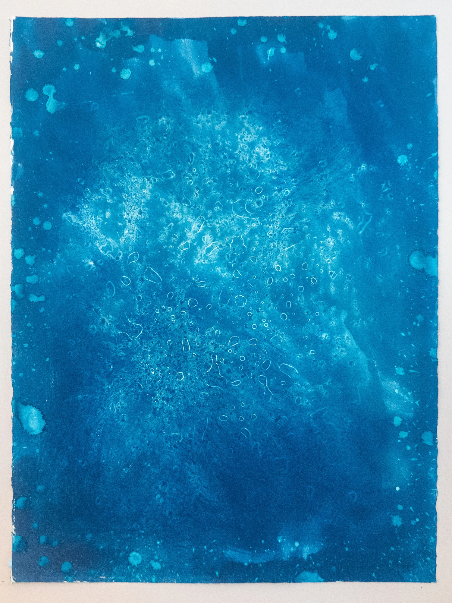 A drift of fine ringed circles falling through mid-blue water, each ring outlined in a paler blue than the field around it.
