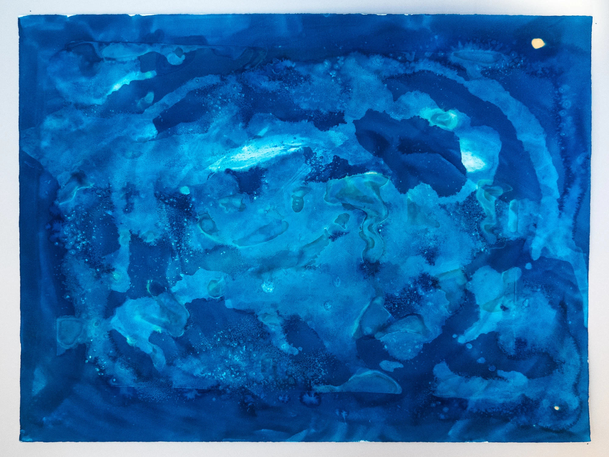 Horizontal bands of blue broken by pale channels, a marsh read from directly above.

