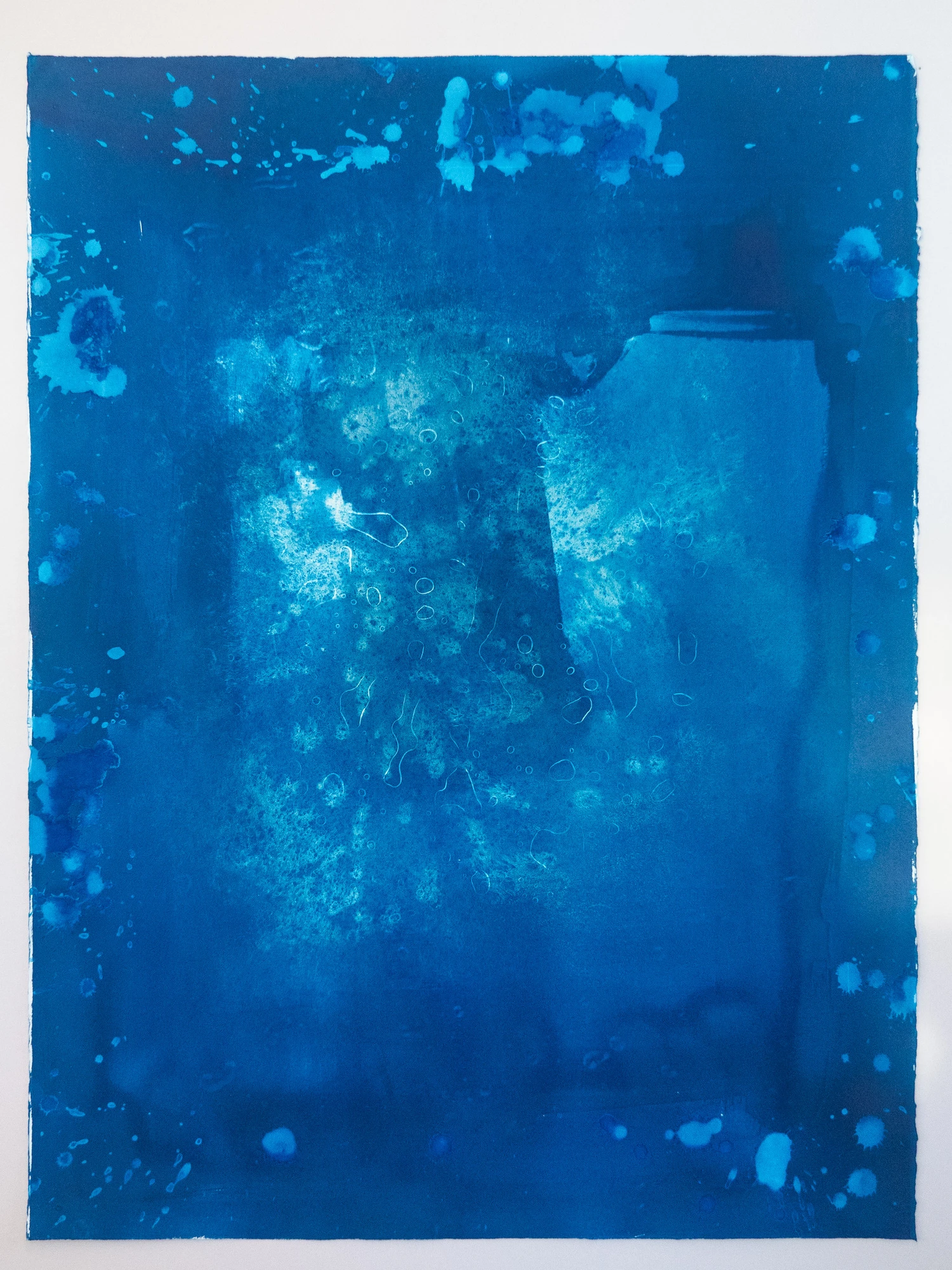 A dark saturated blue field with a paler granular mass at its center, seen as if resting on the seabed looking up.
