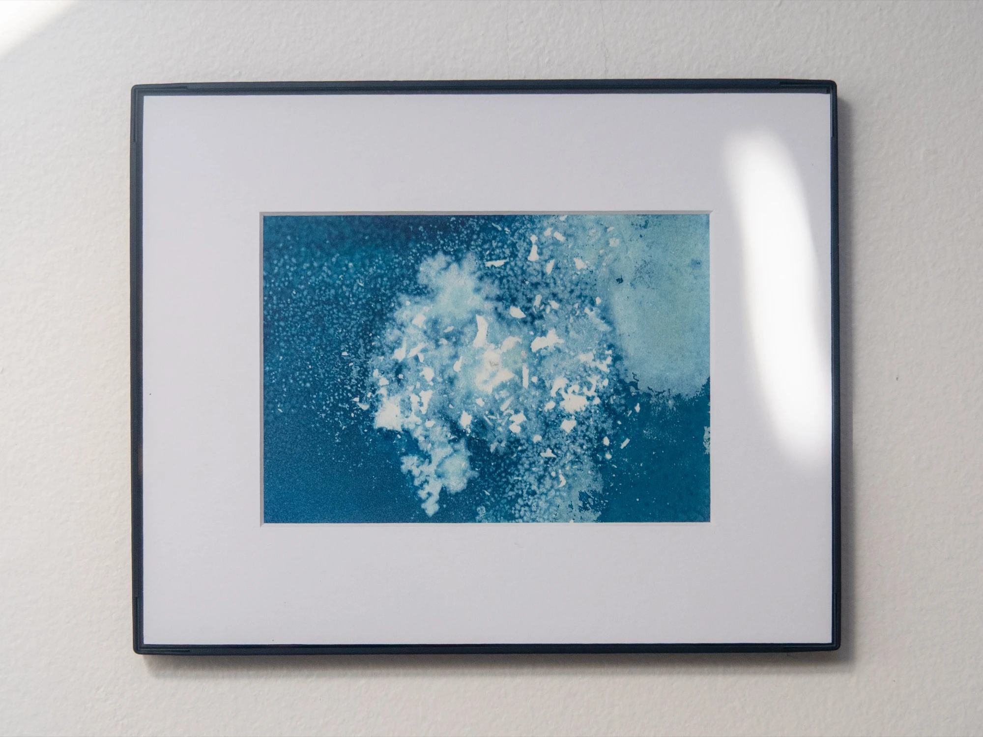 The second panel framed to match, on the same pale wall, a soft band of window light falling across its right edge.
